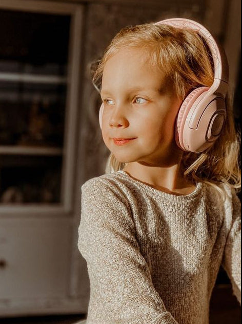 Koptelefoon voor kinderen draadloos bluetooth in roze gedragen door meisje in woonkamer