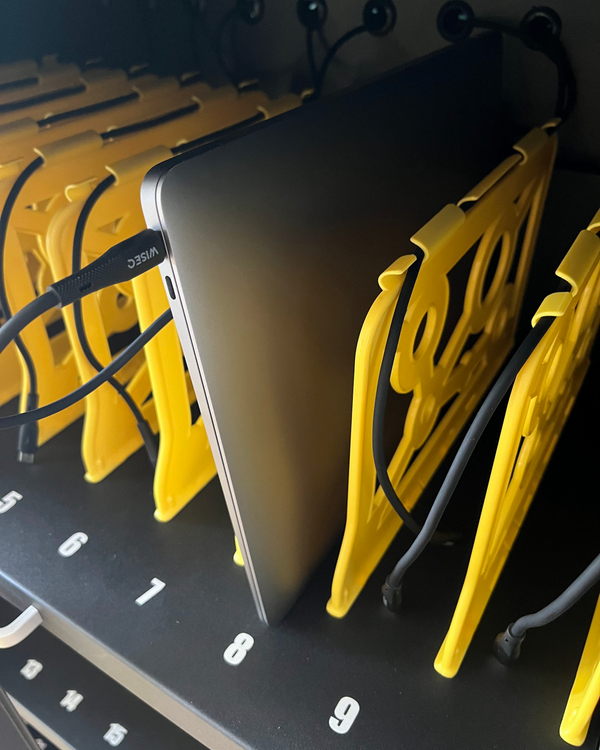 Detail van zwarte tablet en laptop oplaadkar met aangesloten tablet in genummerd vak