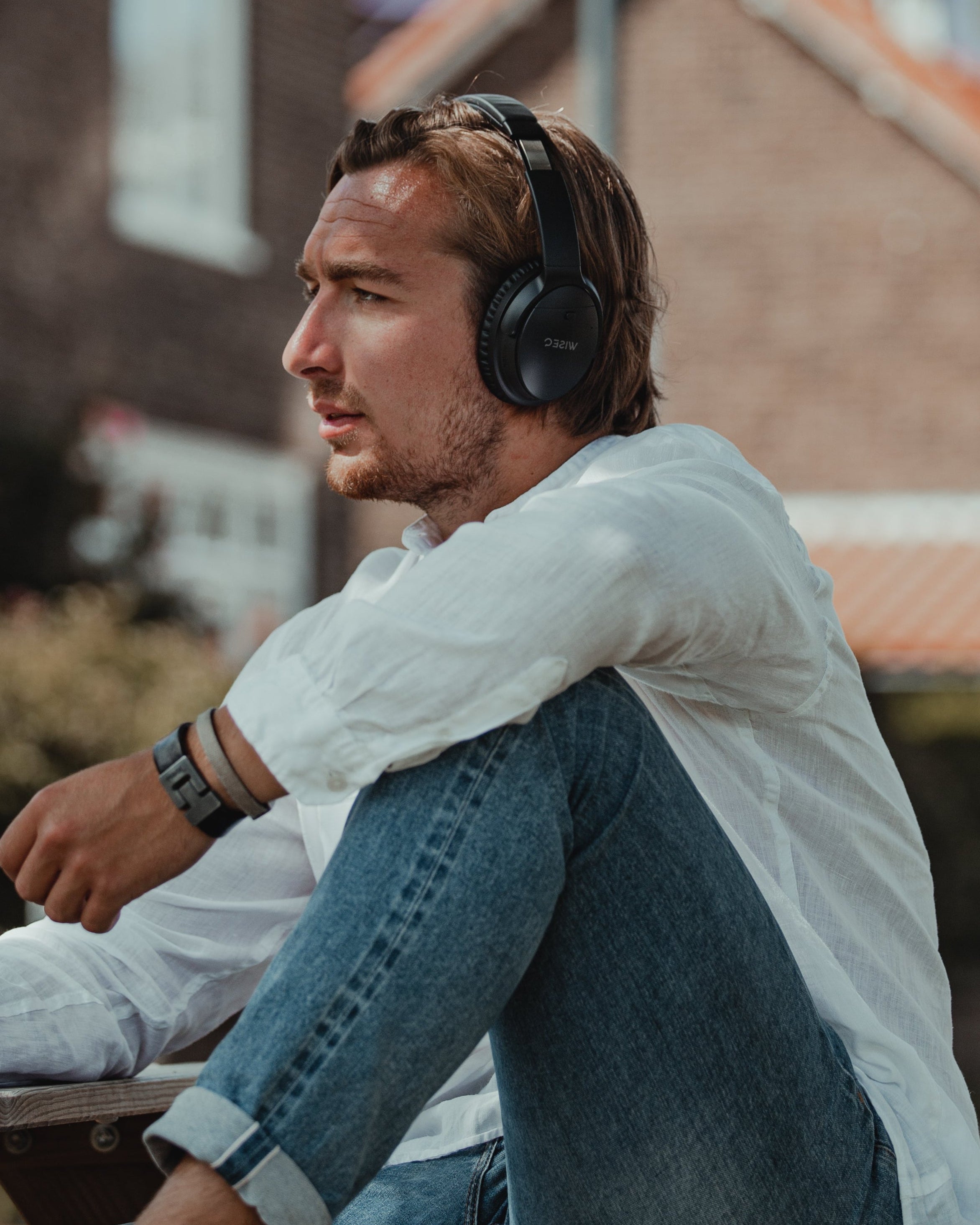 Man draagt WiseQ koptelefoon en zit buiten in een moderne stedelijke omgeving
